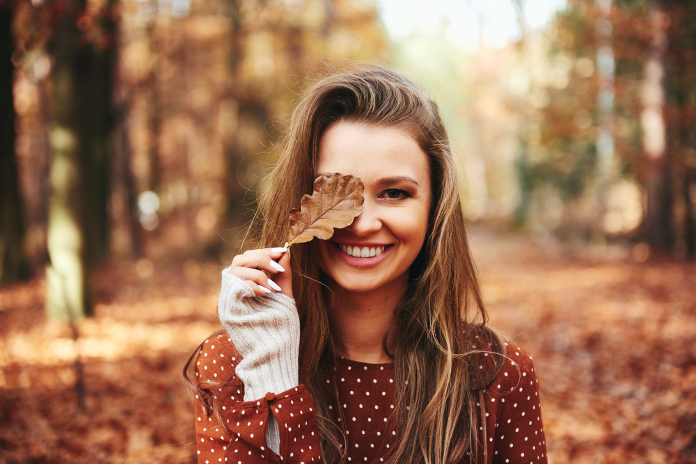 Chica en un bosque sonriendo por su cuidado para el pelo en otoño
